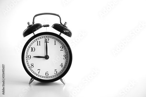 Black vintage alarm clock on table. White background. Wake up concept. An image of a retro clock showing 09:00 pm/am. 