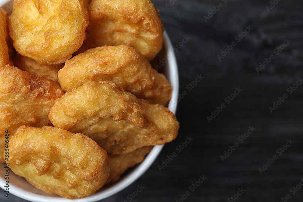 Bucket with tasty chicken nuggets on black wooden table, top view Bucket with tasty chicken nuggets on black wooden table, top view