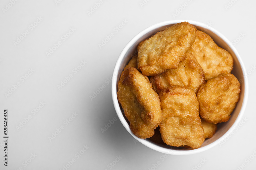 Bucket with delicious chicken nuggets on light background, top view. Space for text Bucket with delicious chicken nuggets on light background, top view. Space for text