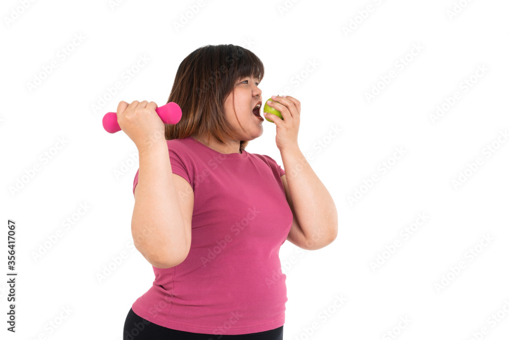 Overweight Asian woman sitting and holding a green apple and dumbbells on isolated white background. Concept of diet, Health care, And eating food that is good for good health, and exercise, workout Overweight Asian woman sitting and holding a green apple and dumbbells on isolated white background. Concept of diet, Health care, And eating food that is good for good health, and exercise, workout