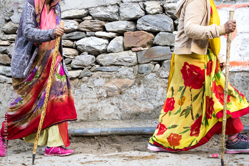 Image of old women walking with the support of stick at mountain region Image of old women walking with the support of stick at mountain region