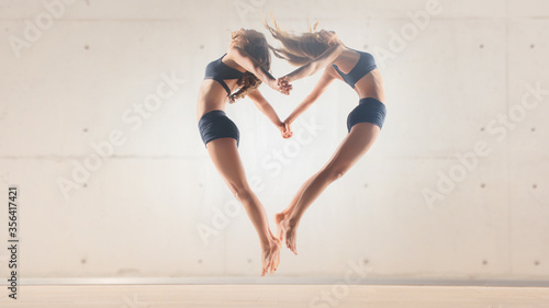 two beautiful girls jump upwards in heart shape