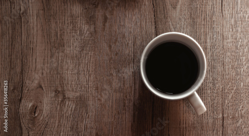 Top view of black coffee in white cup on wooden table. Brown tone photo