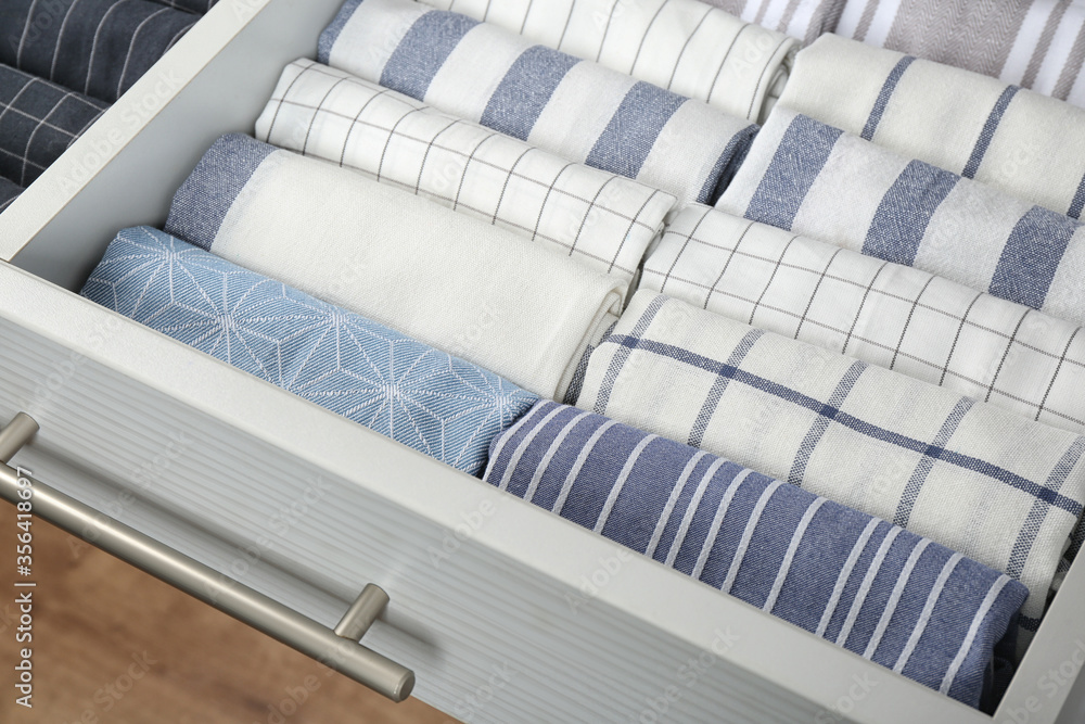 Fototapeta premium Open drawer with folded towels, closeup. Order in kitchen