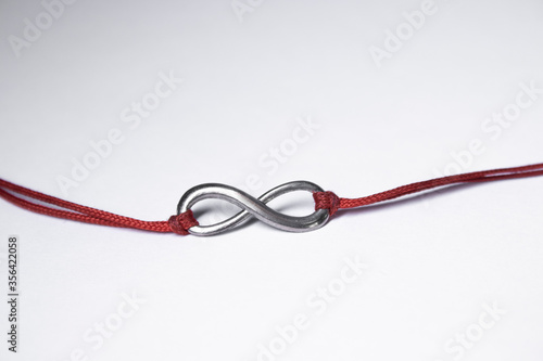 red ribbon bracelet with an infinity sign. jewelry and accessories concept. Isolated, copy space. Macro Shot. High quality photo