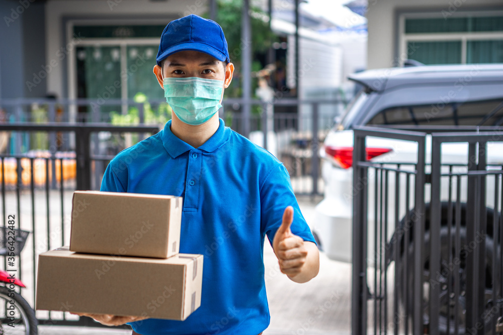 Asian deliveryman is delivering parcel to house her to sign to receive the product After she ordered online during the outbreak of the coronavirus or Covid-19 virus. Asian deliveryman is delivering parcel to house her to sign to receive the product After she ordered online during the outbreak of the coronavirus or Covid-19 virus.