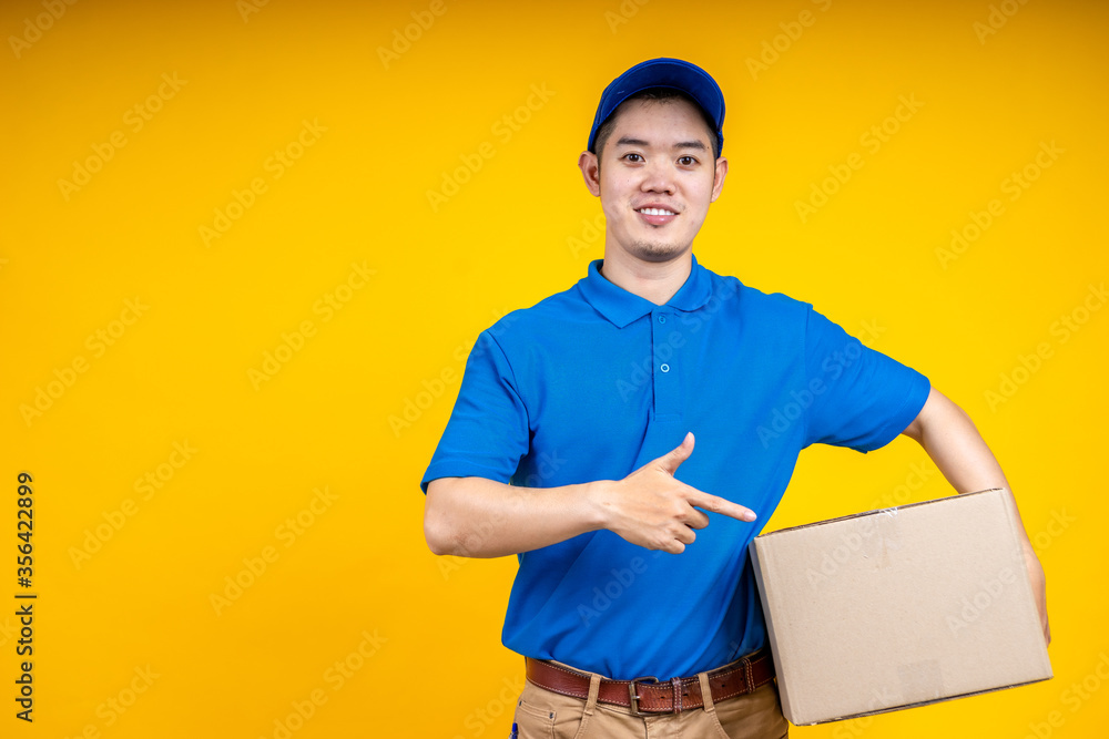 Asian delivery man holding parcel box over yellow isolate background. Work from home and delivery concept. Asian delivery man holding parcel box over yellow isolate background. Work from home and delivery concept.