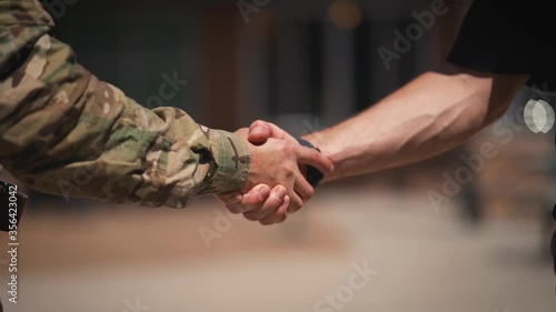 Soldier and civilian arms shaking hands close up slow motion photo