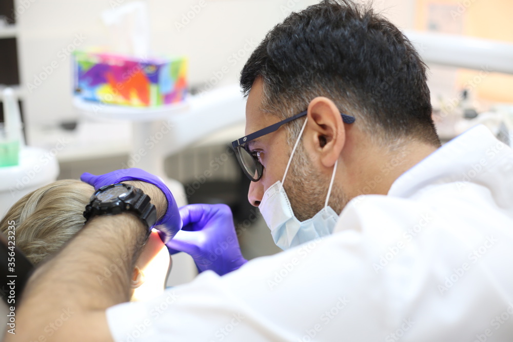 dentist is diagnosing the child while assistant in dental clinic dentist is diagnosing the child while assistant in dental clinic