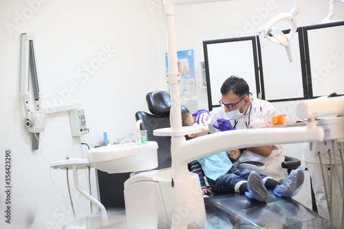 dentist is diagnosing the child while assistant in dental clinic
