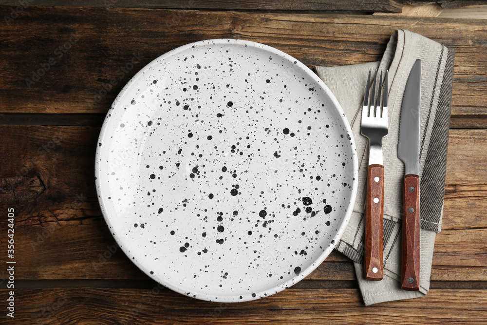 Empty patterned plate with cutlery and napkin on wooden table, flat lay Empty patterned plate with cutlery and napkin on wooden table, flat lay