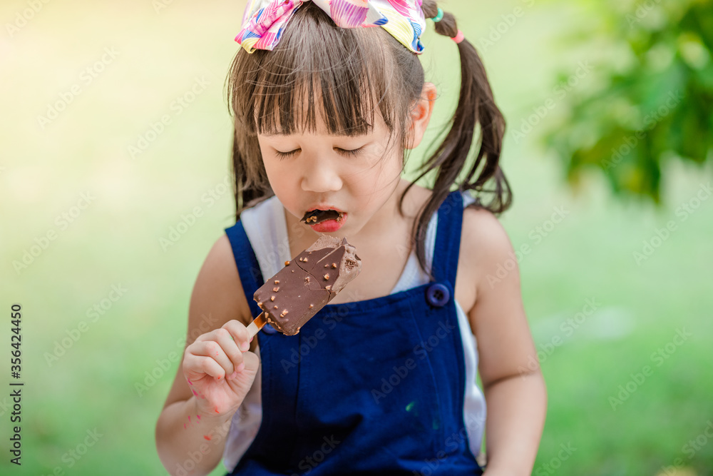 Close up background view Of ASEAN girls eating delicious ice cream, with chocolate flowing on clothes, the concept of self-learning Close up background view Of ASEAN girls eating delicious ice cream, with chocolate flowing on clothes, the concept of self-learning