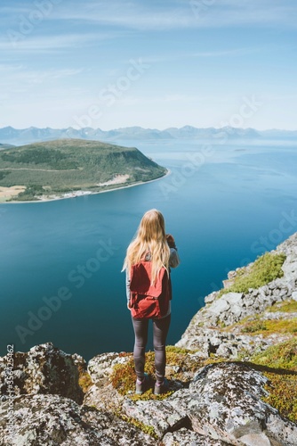 Travel in Norway woman traveler with backpack standing on cliff alone outdoor summer vacations adventure lifestyle solo trip aerial sea fjord landscape © EVERST