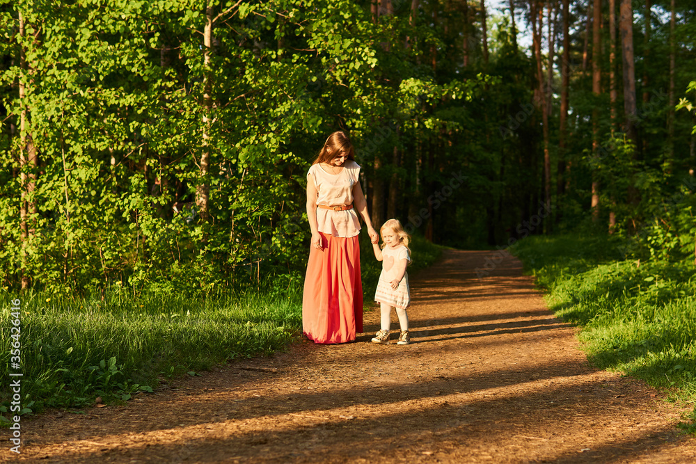 Fototapeta premium mother and little daughter walk along a path in a park