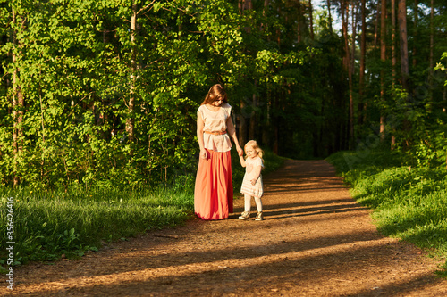 mother and little daughter walk along a path in a park © Evgeny