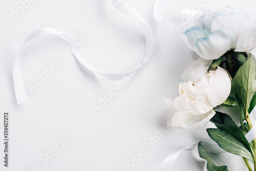 Fototapeta Naklejka Na Ścianę i Meble -  top view of blue and white peonies with ribbon on white background