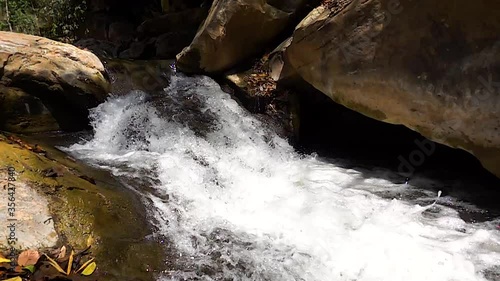 Slow motion, water flowing over round rocks, shadows and sun, protective feeling,