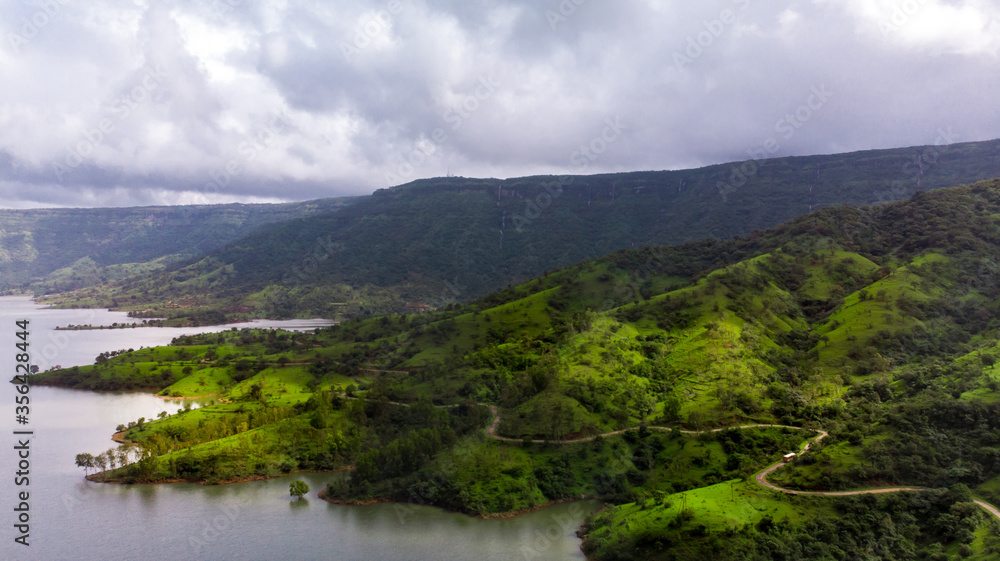 Aerial/Drone View of a river valley and an offbeat holiday resort in green surroundings during Monsoon season in Maharashtra, India.