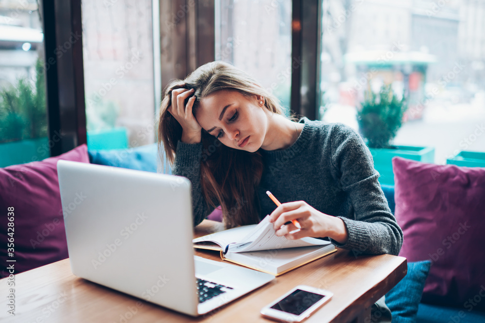 Smiling attractive student spending free time in coffee shop interior on exam preparation Smiling attractive student spending free time in coffee shop interior on exam preparation