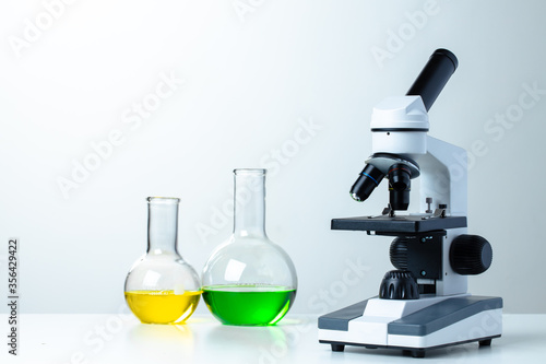 Lab microscope with laboratory glassware on desk