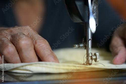 Selective focus on hands of mother old woman create pattern design and the old sewing machine for vintage design