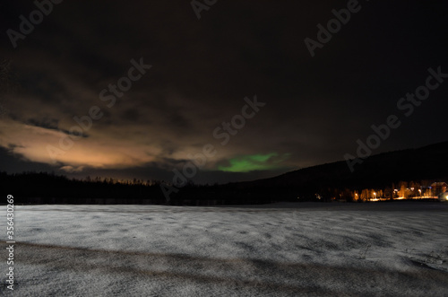 long white snowy field with green northern light in the background