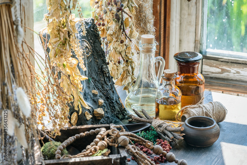 Magic potion bottles, spell book and dried plants on the witch doctor table. Witchcraft.