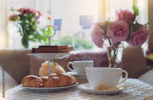Vászonkép Traditional English tea time, Afternoon tea ceremony with cuppa tea, croissants, crackers and biscuits on hight tea stand in pink pastel