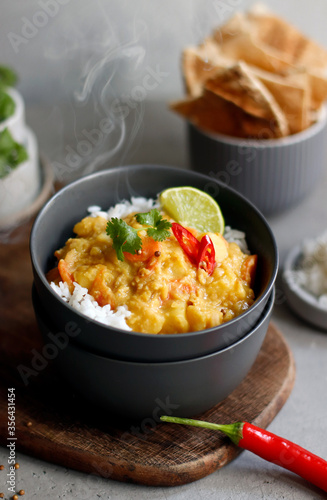 Hot spicy lentil curry in bowl. Vegetable curry with rice, pita bread, spices, herbs. Traditional popular indian curry