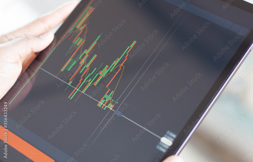 Fototapeta premium Closeup hand holding digital tablet computer with graph of Binary option for trading platform, setective focus