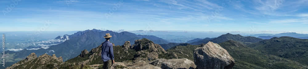 Hiker admiring Serra Fina mountain chain, after ascending to Couto Stone - Itatiaia State Park, Brazil