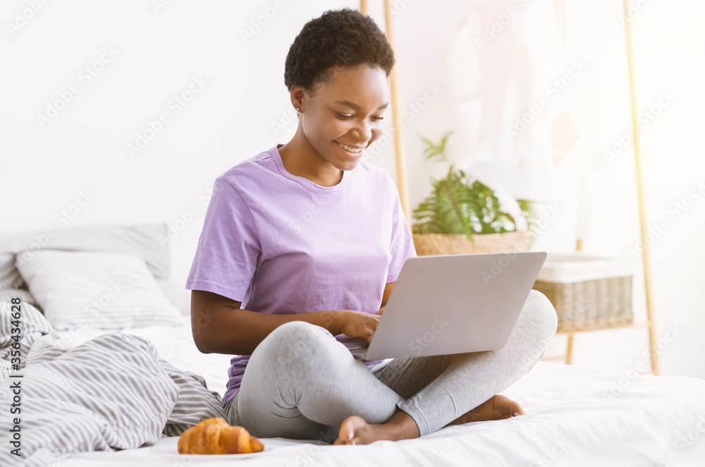 Remote work and viewing webinar from home. Girl sitting on bed with laptop Remote work and viewing webinar from home. Girl sitting on bed with laptop