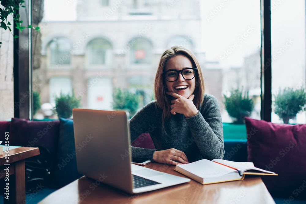Smiling attractive student spending free time in coffee shop interior on exam preparation Smiling attractive student spending free time in coffee shop interior on exam preparation