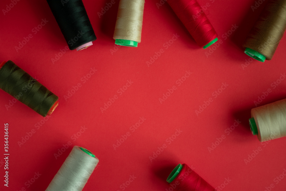 Fototapeta premium Bobbins on red background. Sew and tailoring concept, sewing tools, needlework.