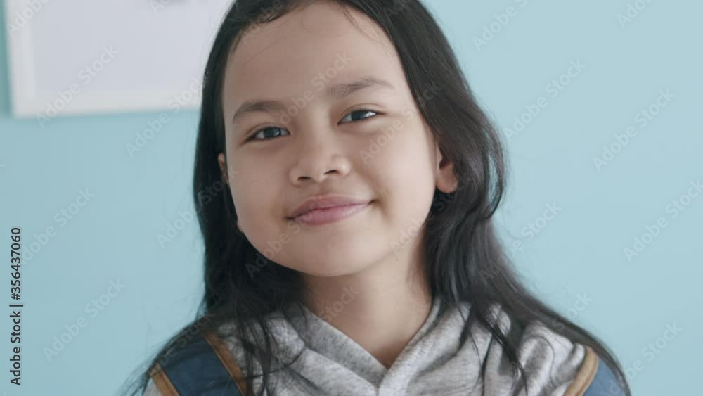 Happy Asian little girl smile holding book and backpack to school	