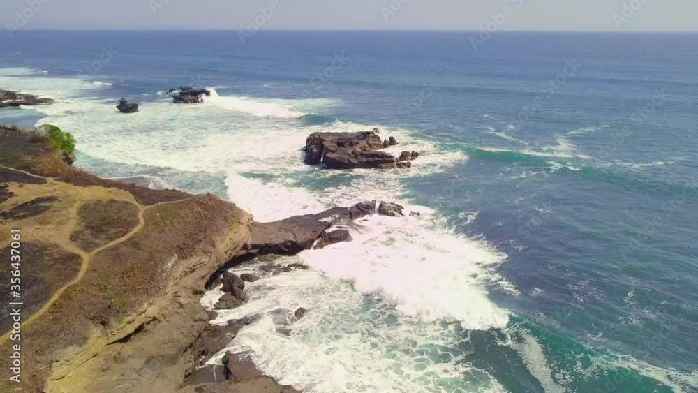 Picturesque aerial view of blue ocean with waves crashing on the shore and green rice fields. Peaceful tropical scene, amazing landscape and seascape. serene natural scenery. Picturesque aerial view of blue ocean with waves crashing on the shore and green rice fields. Peaceful tropical scene, amazing landscape and seascape. serene natural scenery.