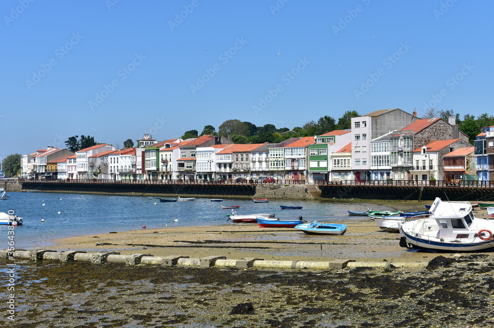 Fishing village with wooden boardwalk, colorful houses and boats with blue sky. Mugardos, Galicia, Spain.