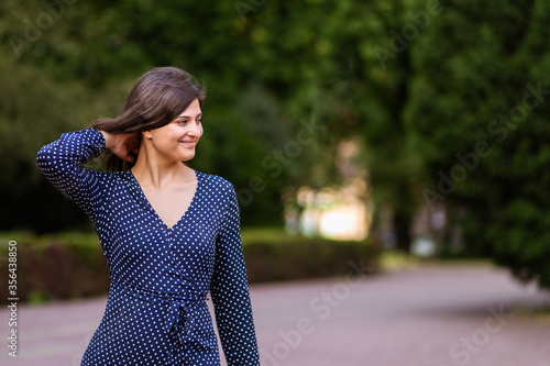 Beautiful young woman adjusting hair while walking and smiling