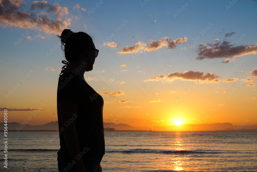 Silhouette of a woman contemplating a beautiful sunset in Ilha do Mel, Paraná, Brazil