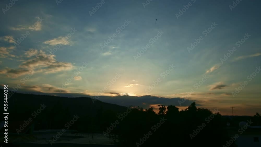 small kite float hight under bright cloudy sunset sky above dark low mountains small kite float hight under bright cloudy sunset sky above dark low mountains