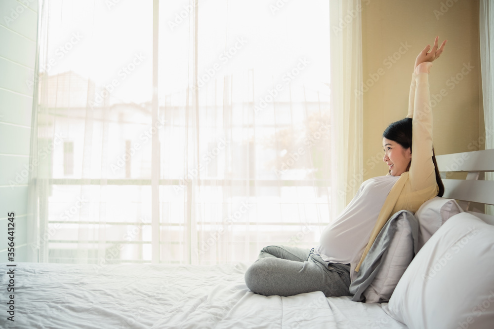 Happy pregnant woman asian with leg up while lying on bed Leave space Light exercise Smiling and wearing fresh Happy pregnant woman asian with leg up while lying on bed Leave space Light exercise Smiling and wearing fresh
