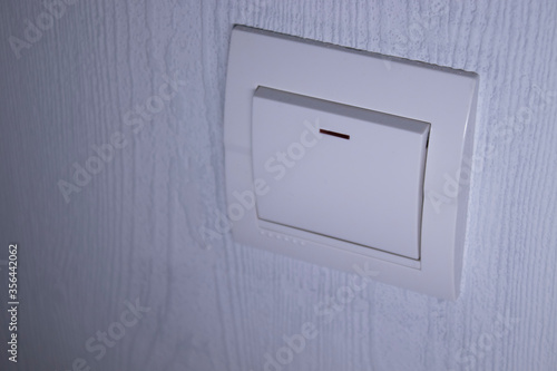 Plastic mechanical white light switch, installed on a light gray wall. High quality photo