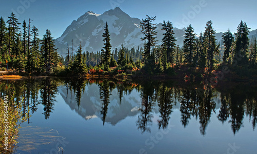 This landscape photo is of Picture Lake at Heather Meadows on Mt. Baker Washington in autumn. Breath taking mountain is reflected off the water of the lake and fall foliage surrounds the edges. 