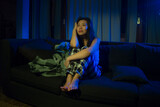 dramatic portrait of young beautiful sad and depressed Asian Korean woman lying in pain at living room sofa couch broken heart suffering depression and anxiety