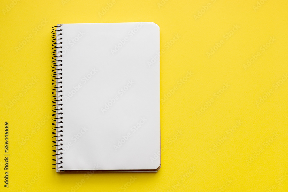 Spiral notebook with blank empty white sheets on a bright yellow background, top view, flat lay with copy space Spiral notebook with blank empty white sheets on a bright yellow background, top view, flat lay with copy space