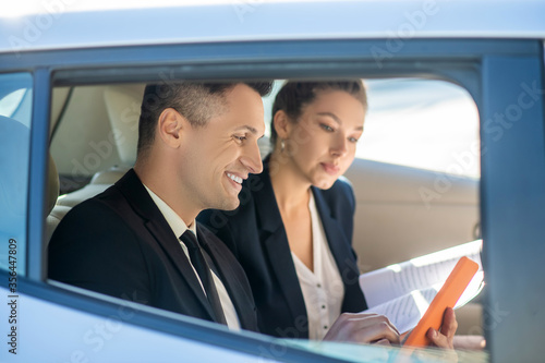 Attractive man with tablet and attentive woman with documents in car