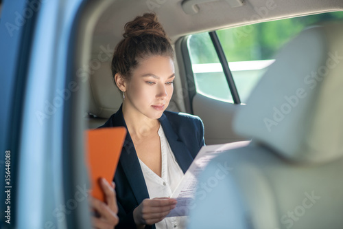 Serious business woman studying a document in a car. © zinkevych
