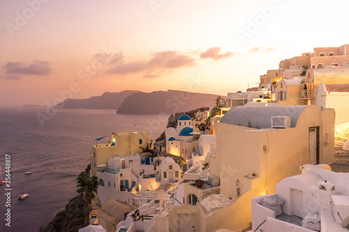 Sunset view of Oia with blue domes ( Saint Nikolaos Peramataris )and bell tower, Thirasia in the back, Santorini island, Cyclades, Greece 