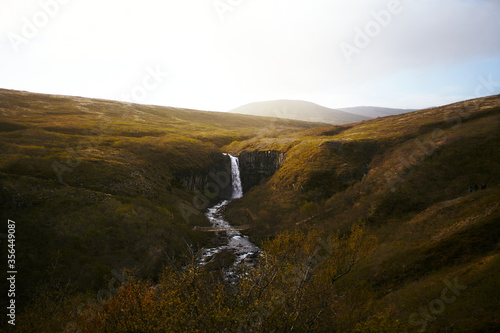 Obraz na płótnie Icelandic landscape and Svartifoss, Black Fall in the middle. Panorama with bridge over the river and waterfall. w salonie