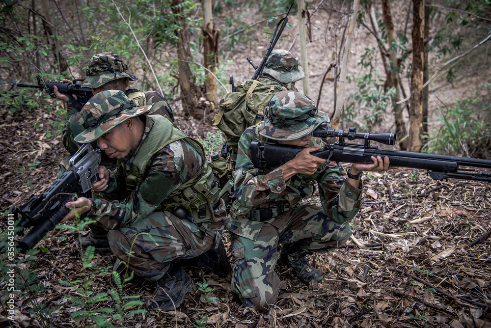 Team of army soldier with machine gun moving in the forest,Thai militia soldier in combat uniforms in the wood,Wander the patrol sloping in the rainforest. Team of army soldier with machine gun moving in the forest,Thai militia soldier in combat uniforms in the wood,Wander the patrol sloping in the rainforest.